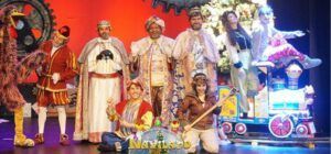 Elenco de Naviland, el Musical de los Reyes Magos, posando en el escenario con los Reyes Magos, un gran pájaro, y otros personajes junto a un tren de juguete.