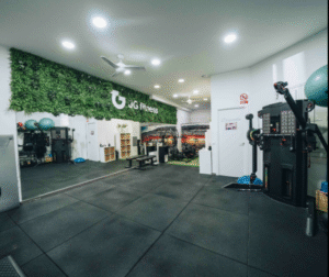 Interior de gimnasio con equipos, jardín vertical y zona de diagnóstico.