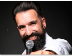 Miguel Lago sonriendo mientras sostiene un micrófono, durante su espectáculo de stand-up comedy.